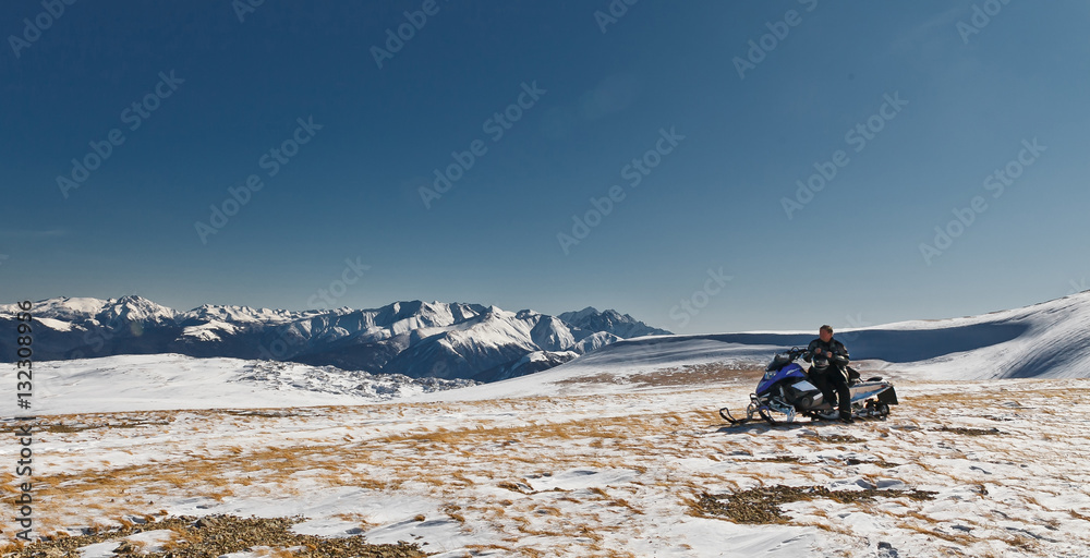 A lone rider on a snowmobile on a mountain top in the National Nature Reserve in Adygea, Russia.