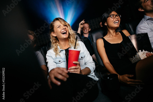 Laughing young people watching film in theater