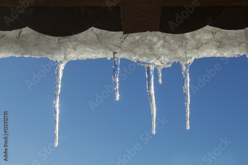 Snowy ice Icicles hanging on a roof house