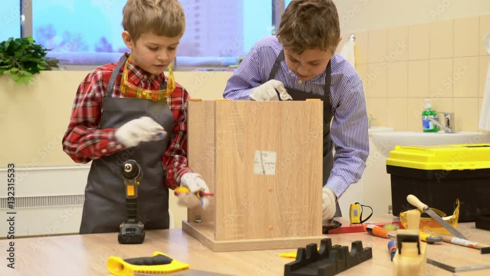 Young school boys tightening screws in wooden stool at a Labor lesson Young school boys tightening screws in wooden stool at a Labor lesson