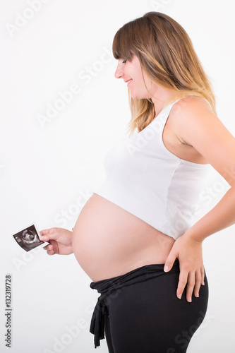 A pregnant woman looking at her unborn baby's ultrasound scan. Studio portrait on white background