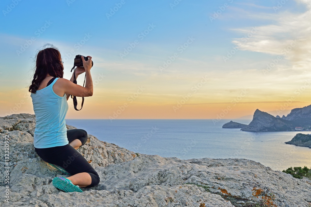 Girl tourist photographing the landscape at sunset