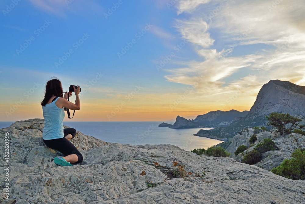 Girl tourist photographing the landscape at sunset