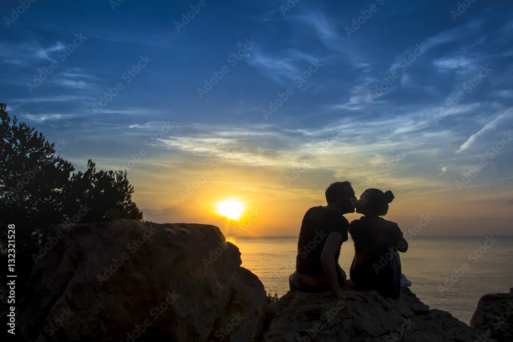 Male and female couple kissing at sunriee