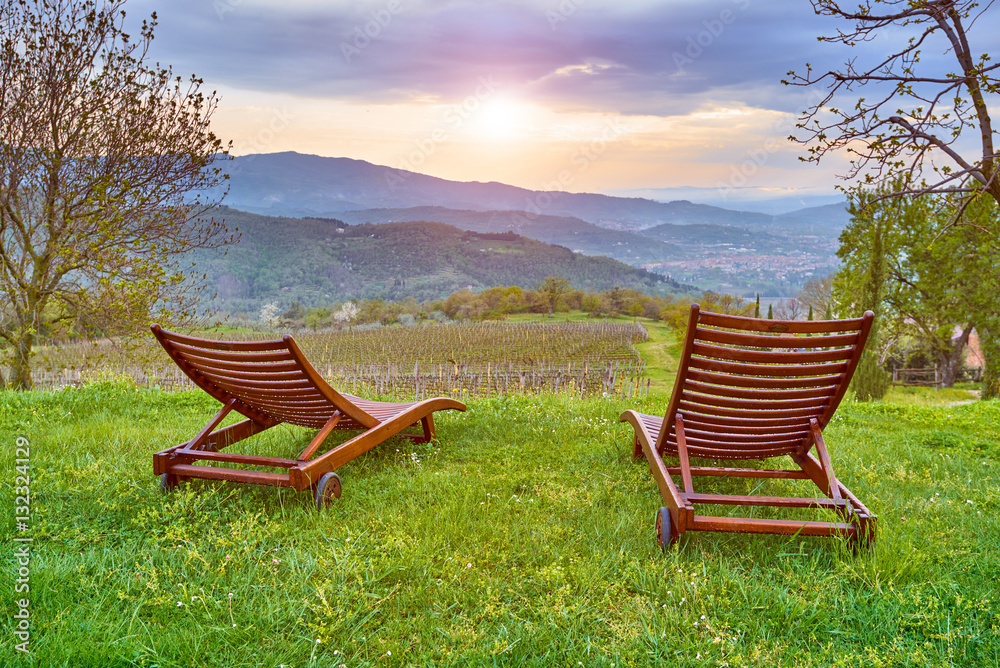 The two reclining chairs sit on the grass overlooking the valley and the hills