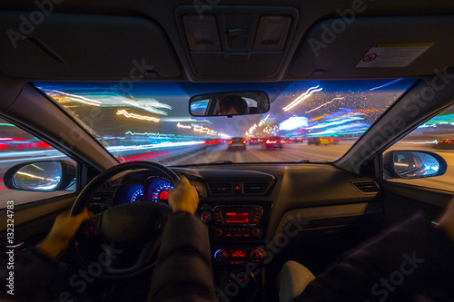 Night road view from inside car natural light street and other cars is motion blurred. © pozdeevvs