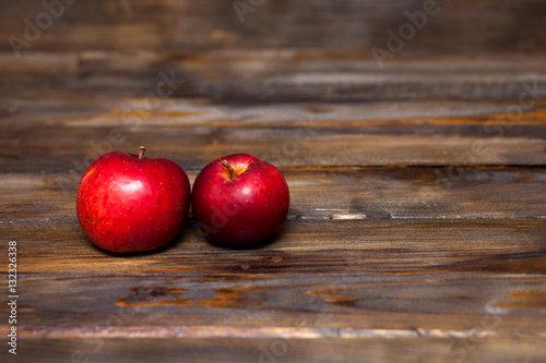 Two red apples on a wooden background