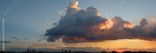 Industrial skyline rim below pastel color cumulonimbus clouds su