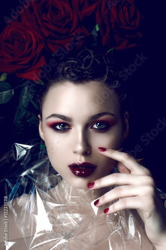 Beauty Fashion Model Woman face. Portrait with Red Rose flowers. Red Lips and Nails. Beautiful Brunette Woman with Luxury Makeup, perfect skin. Valentine.