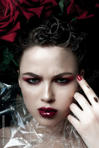 Beauty Fashion Model Woman face. Portrait with Red Rose flowers. Red Lips and Nails. Beautiful Brunette Woman with Luxury Makeup  perfect skin. Valentine.
