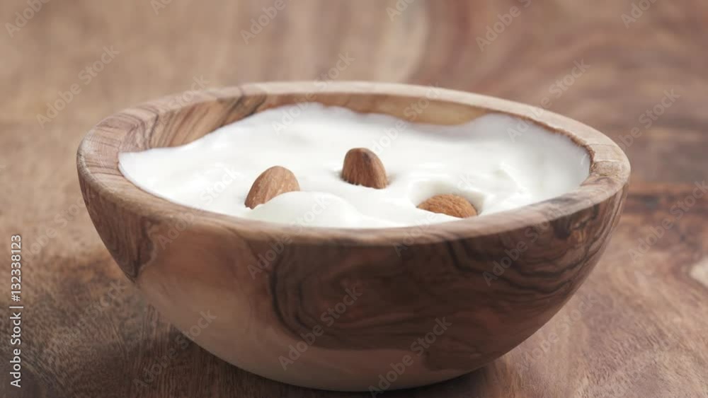 almonds falling into yougurt cream in bowl on table in slow motion, 180fps prores footage almonds falling into yougurt cream in bowl on table in slow motion, 180fps prores footage