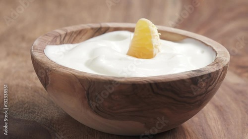 clementine falling into yougurt cream in bowl on table in slow motion, 180fps prores footage photo