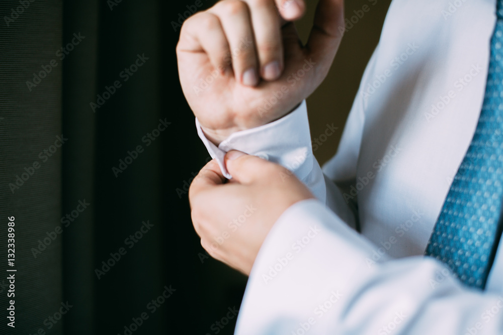 Man buttoning on the sleeve of his shirt. Zip up the cufflink. Men's style.