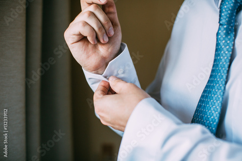Man buttoning on the sleeve of his shirt. Zip up the cufflink. Men's style.