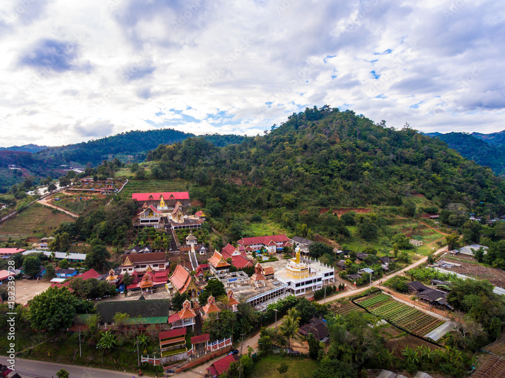 Aerial View of Thai Temple in front of a Mountain and Small Vill