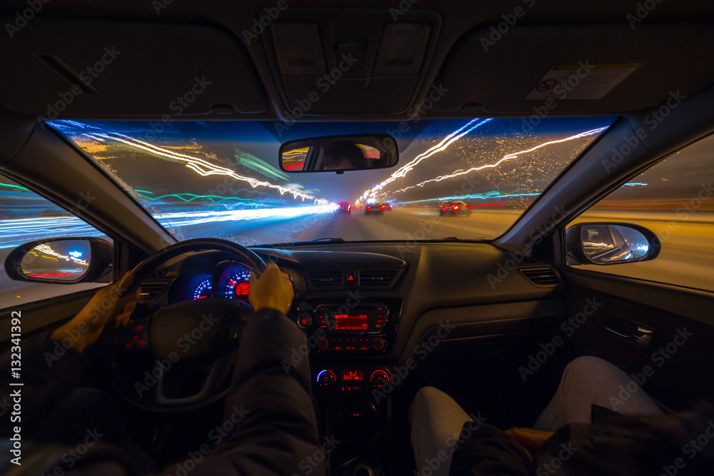 Night road view from inside car natural light street and other cars is motion blurred.