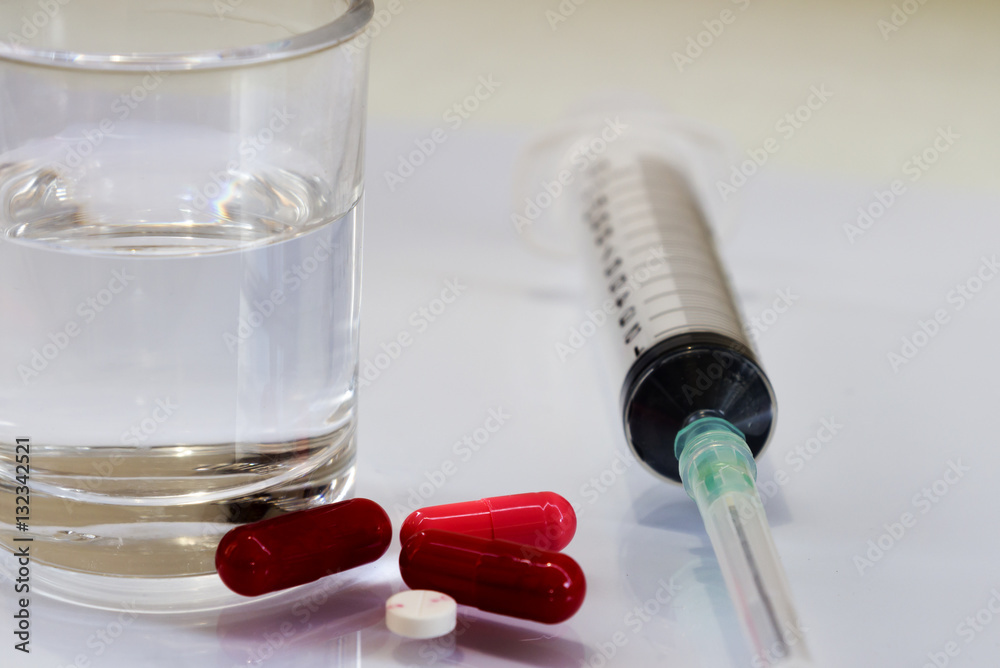 Pills and syringes for treating patients on a white background. Pills and syringes for treating patients on a white background.