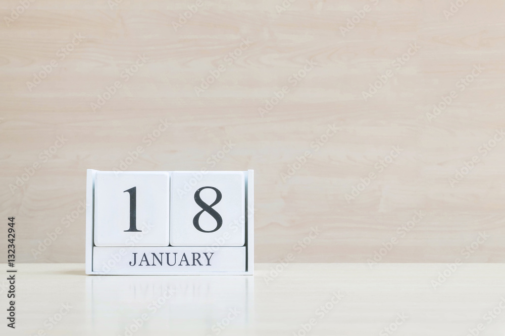 Closeup surface white wooden calendar with black 18 january word on blurred brown wood desk and wood wall textured background with copy space , selective focus at the calendar Closeup surface white wooden calendar with black 18 january word on blurred brown wood desk and wood wall textured background with copy space , selective focus at the calendar
