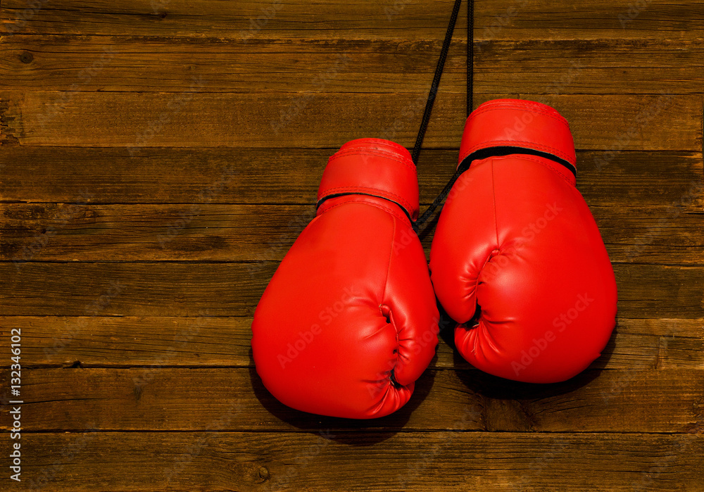 Two red boxing gloves hung on a wooden brown background, empty space