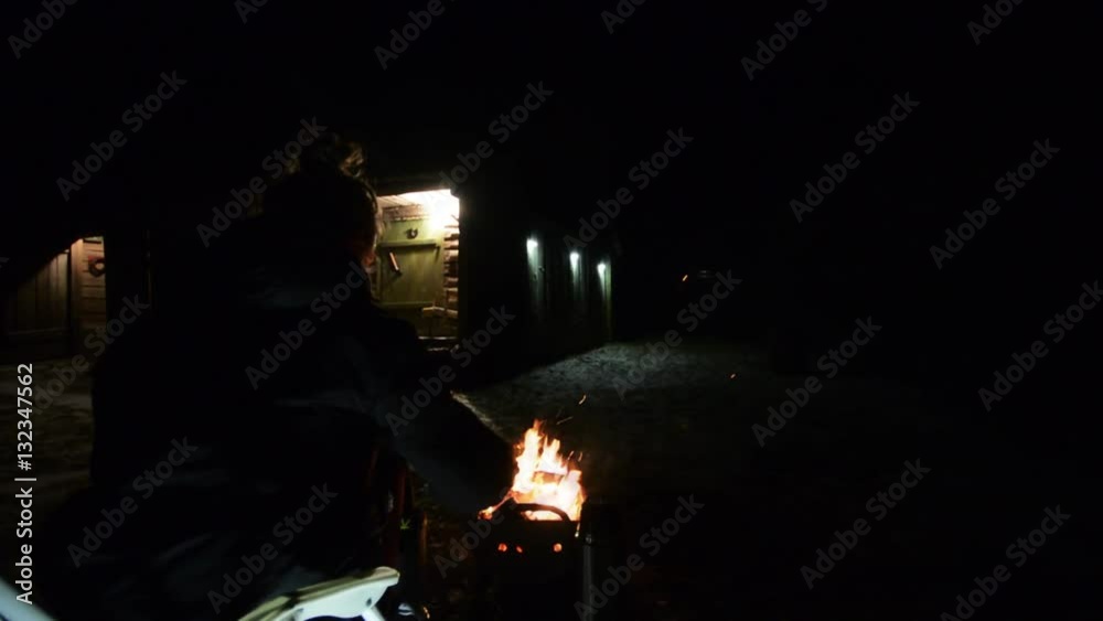 Woman sitting front of campfire with cup of tea. Shot with a slider. Woman sitting front of campfire with cup of tea. Shot with a slider.