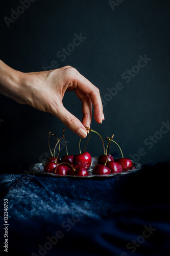 Hand Picking Red Cherries from Silver Platter