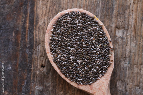 Healthy chia seeds in spoon on wooden table