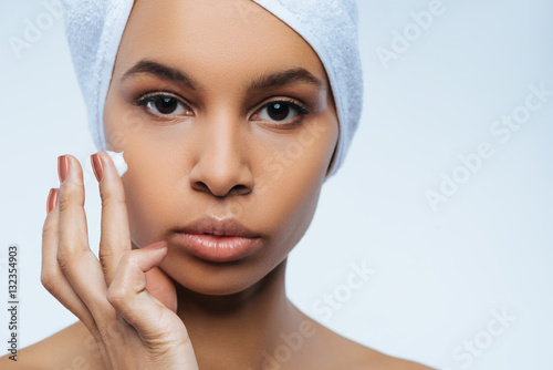 Attractive nice woman using moisturizing cream
