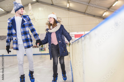 Happy couple holding hands on skating rink