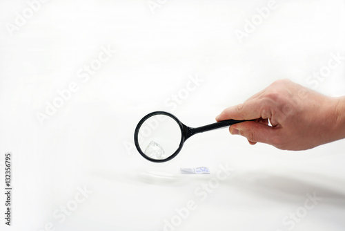 Mans hand with magnifying glass.