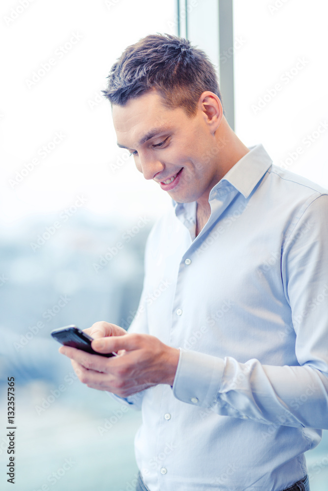 smiling businessman with smartphone in office smiling businessman with smartphone in office