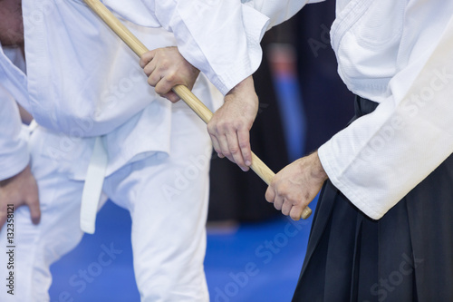 Bild auf Leinwand People practice Aikido with wooden jo on martial arts training seminar