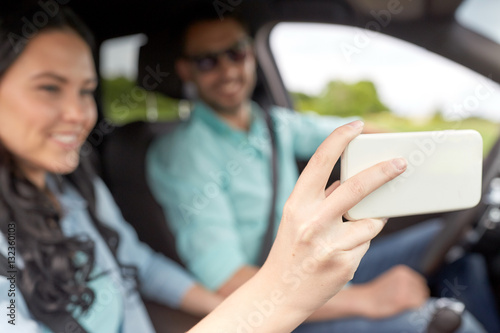 couple driving in car and taking smartphone selfie