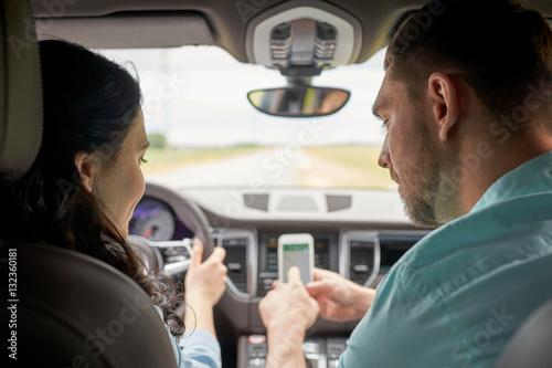 happy man and woman with smartphone driving in car