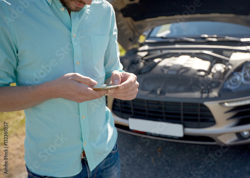 close up of man with smartphone and broken car