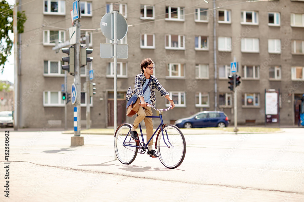 Fototapeta premium young hipster man with bag riding fixed gear bike