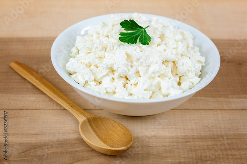 Fresh cottage cheese in a white bowl with spoon