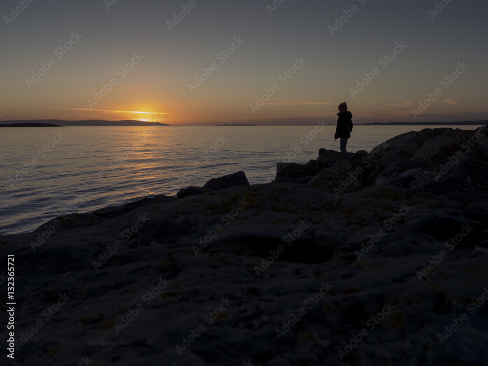 Teenager silhouette at sunset on a sea-shore.