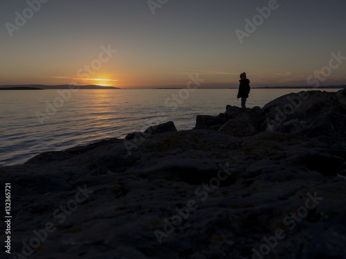 Teenager silhouette at sunset on a sea-shore.