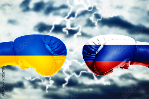 Governments conflict concept. Boxing gloves colored in Ukrainian and Russian flags on sky background