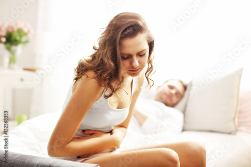 Woman having stomachache in bedroom