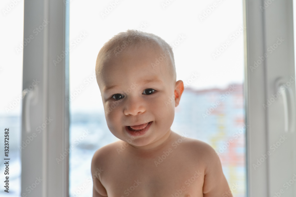 Portrait of a happy little boy standing near window