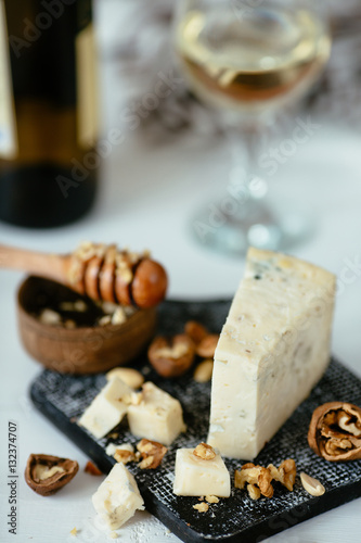 Cheese.  Italian blue cheese Gorgonzola on a wooden background table with honey, nuts and glass of white wine