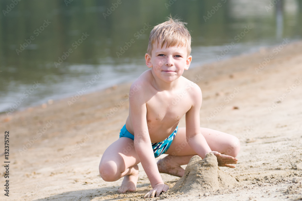 Little boy on the beach plays with sand