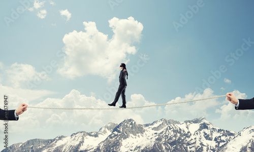 Business concept of risk support and assistance with man balancing on rope