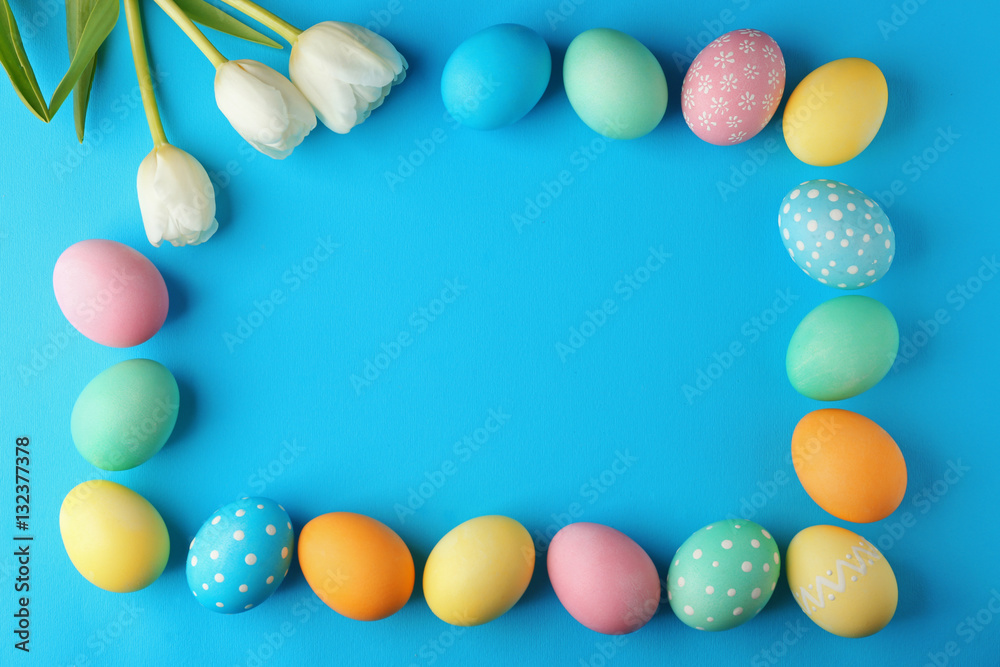 Frame of decorated Easter eggs and flowers on blue background Frame of decorated Easter eggs and flowers on blue background