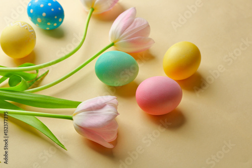 Colourful Easter eggs and flowers on beige background