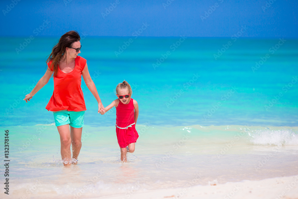 Mother and little daughter enjoying time at tropical beach