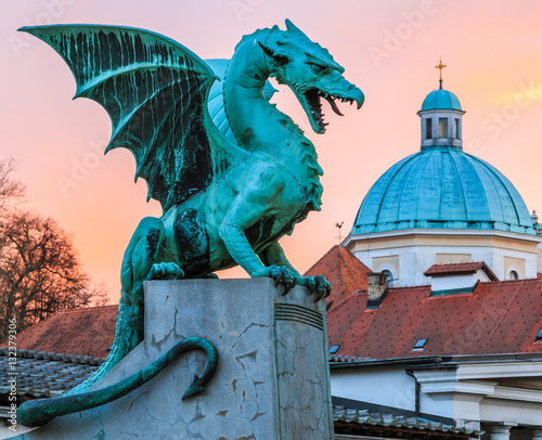 Dragon on the Dragon bridge (Zmajski most) in Ljubljana with the cathedral of st. Nicolai in the background as sunset
 photo