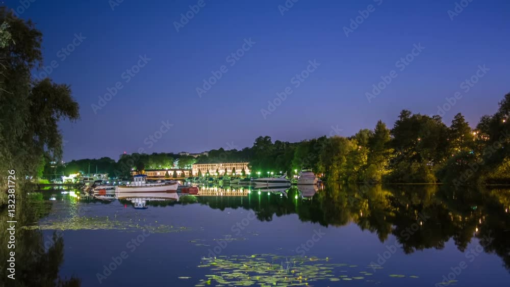 Time Lapse of quayside river at night. Small harbor with boats, castle in the background