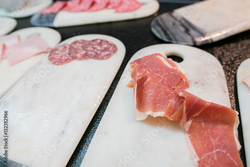 a pile of different spanish embutido, jamon, chorizo and lomo embuchado, typical cold meat on white Granite plate / spanish food. photo